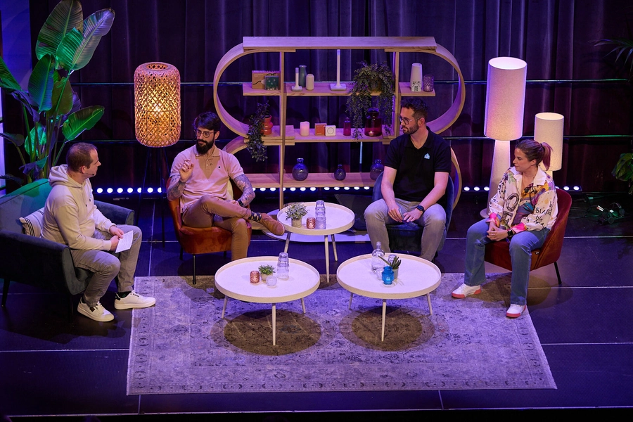 Four speakers—Frenck, JLo, Matthias, and Laura—seated onstage in a panel discussion, talking through the new roadmap, with low tables and a softly lit set behind them.