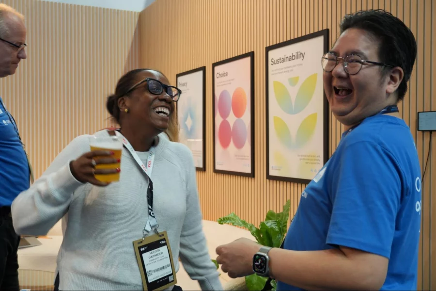 Two people laughing together in front of the framed Privacy, Choice, and Sustainability posters.