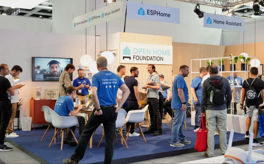 A busy Open Home Foundation booth, with visitors and staff in blue T-shirts below Home Assistant and ESPHome signs.